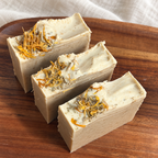 Elevated view of The Herbalist handmade soap bars and golden botanical decoration